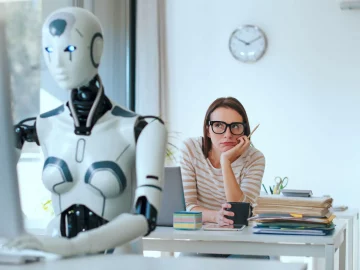 AI agent sitting at computer desk with woman staring at her from behind.