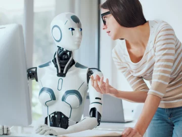 AI robot looking at woman working at a computer