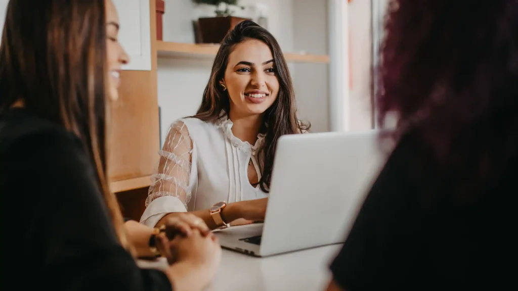Woman behind laptop talking with people in office