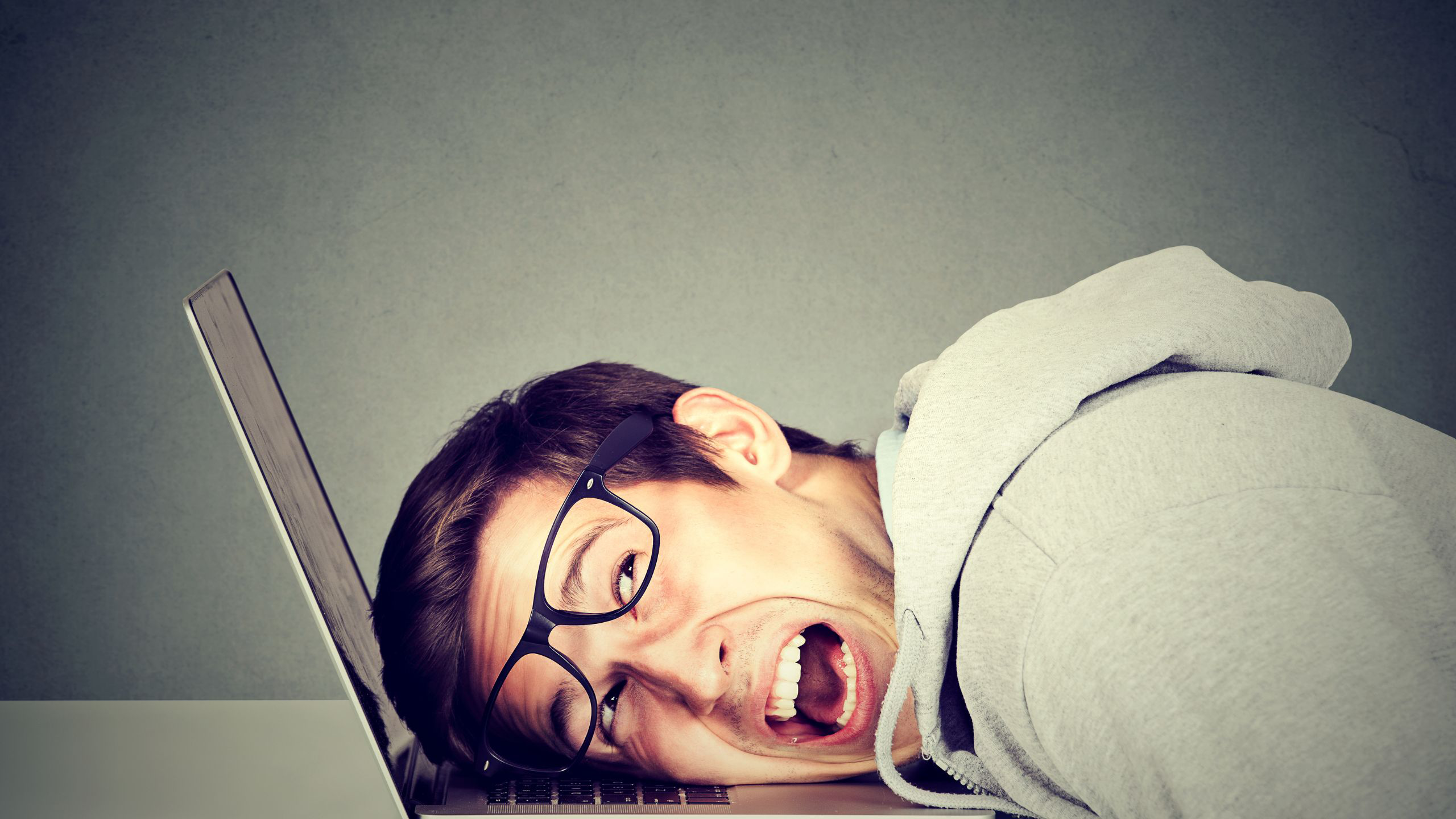 Man frustrated at computer laying his head on the keyboard